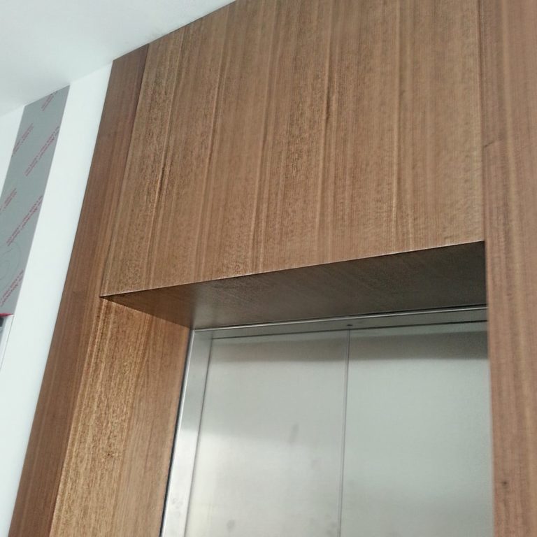 a wall paneling with dark wood veneer over an elevator door