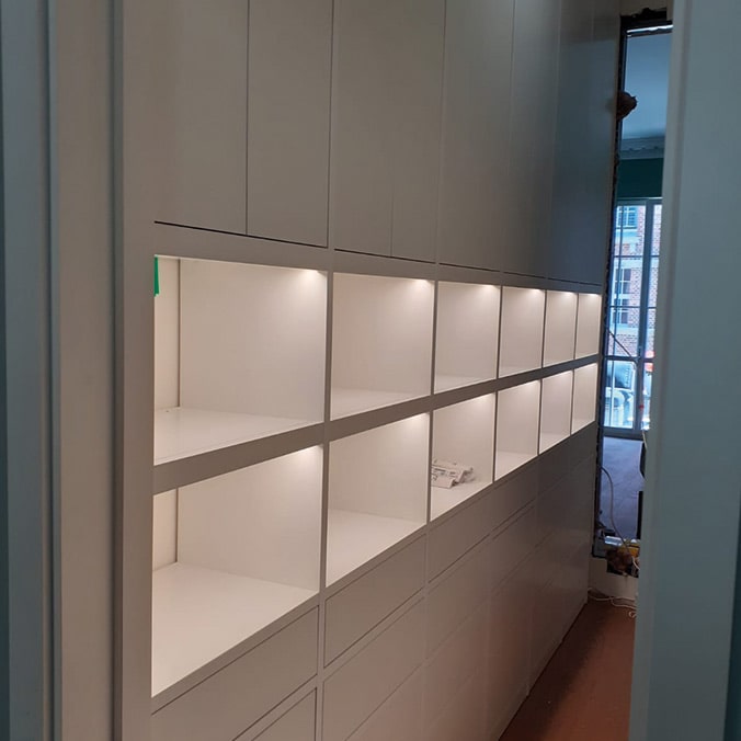 an illuminated white wall built-in cabinet