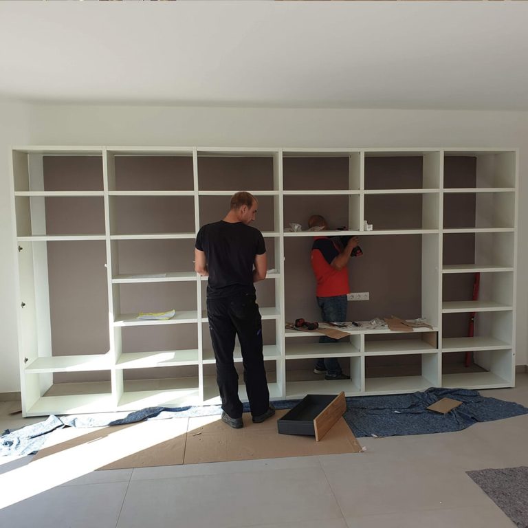 two furniture assemblers assemble a shelving system