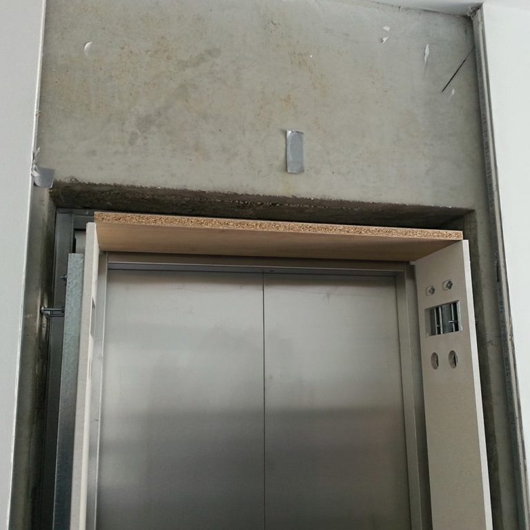 a rough surface above an elevator door in preparation for wall panel installation
