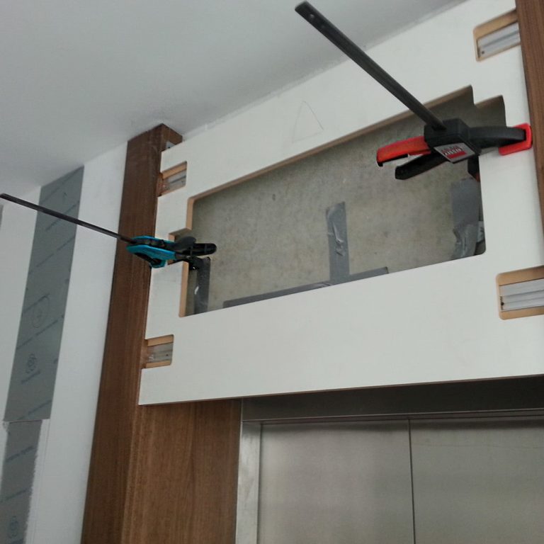 Two clamps above an elevator door serve for panel mounting