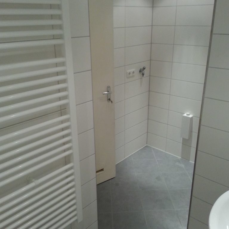 a ready tiled and installed bathroom with light tiles