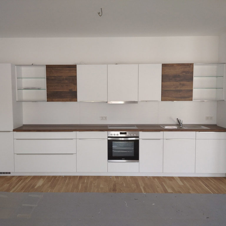 a perfectly assembled kitchen front in white and with wooden work tops