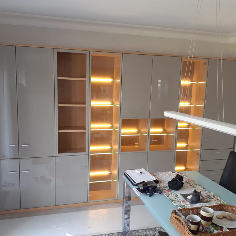 a white modern built-in cupboard with many shelves and lighting units