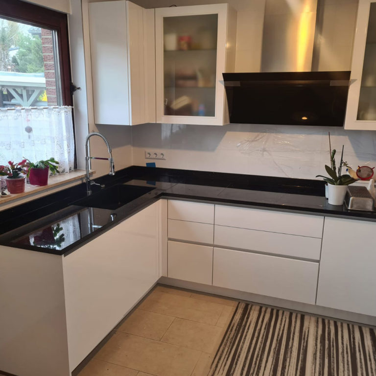 L-shaped kitchen unit with dark glossy worktops and light body