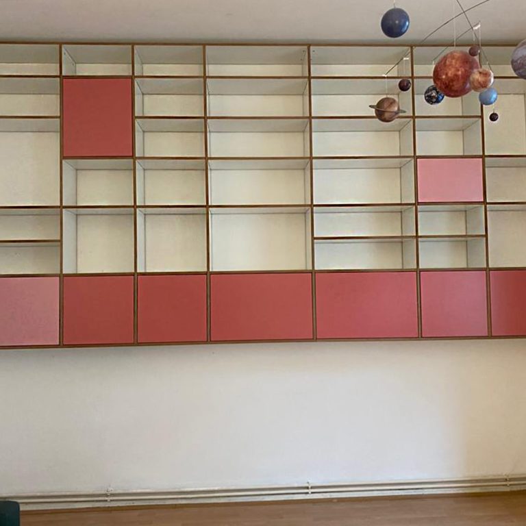 a modern wall shelving system with open units and some reddish fronts