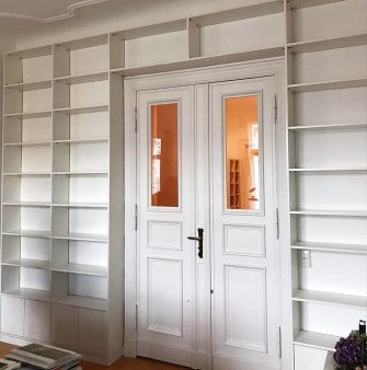 a mounted shelf system in white frames a large room door
