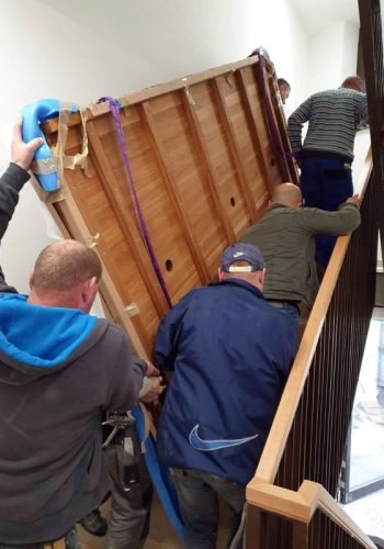As part of furniture logistics, furniture packers carry a tabletop up a flight of stairs